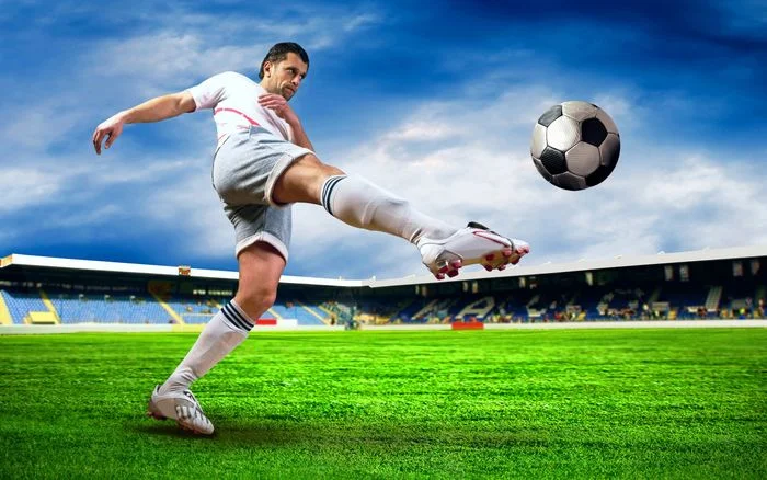 Cầu thủ bóng đá tung cú sút trên sân cỏ